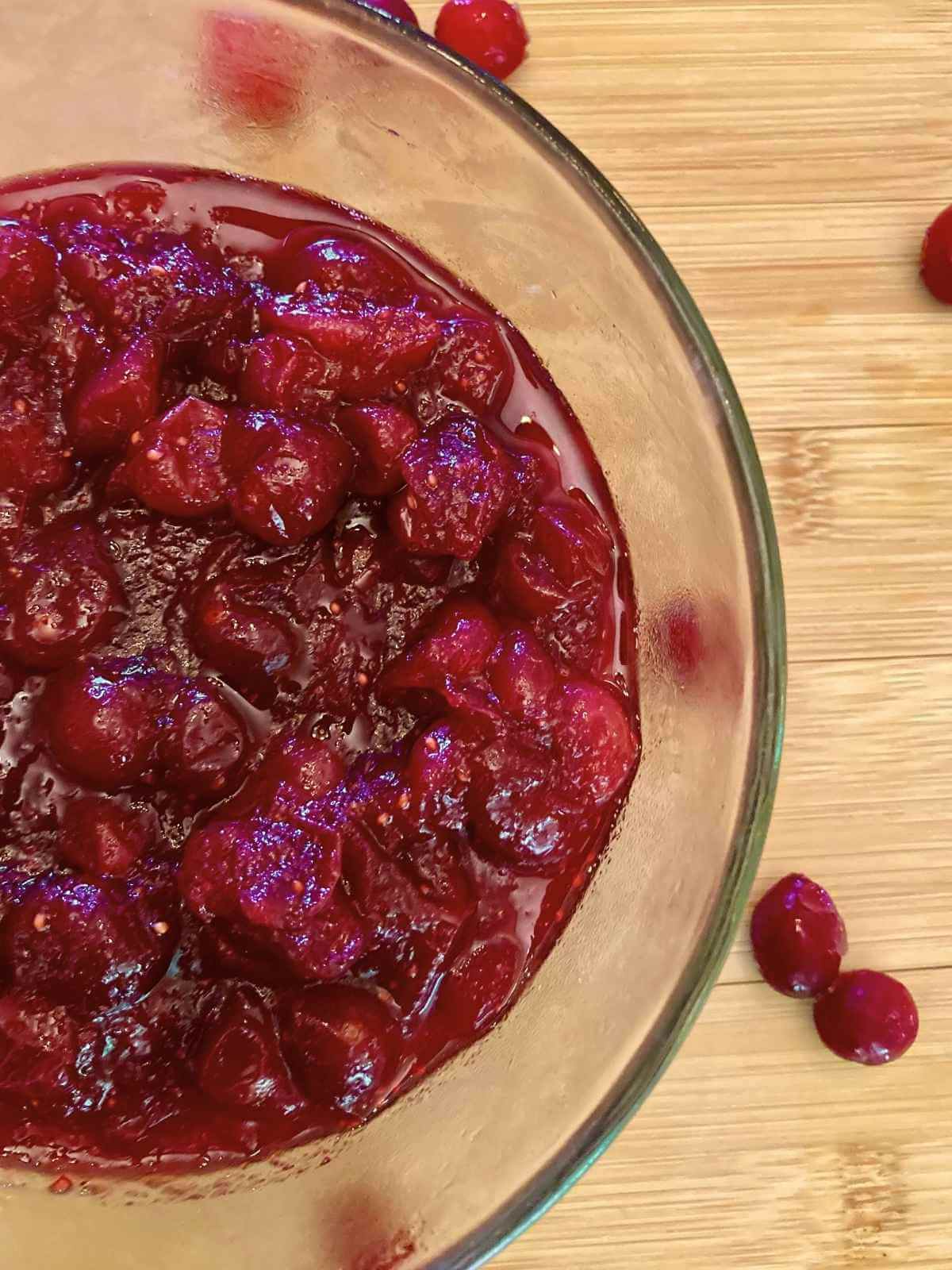 Refined sugar-free cranberry sauce in a glass bowl surrounded by cranberries.
