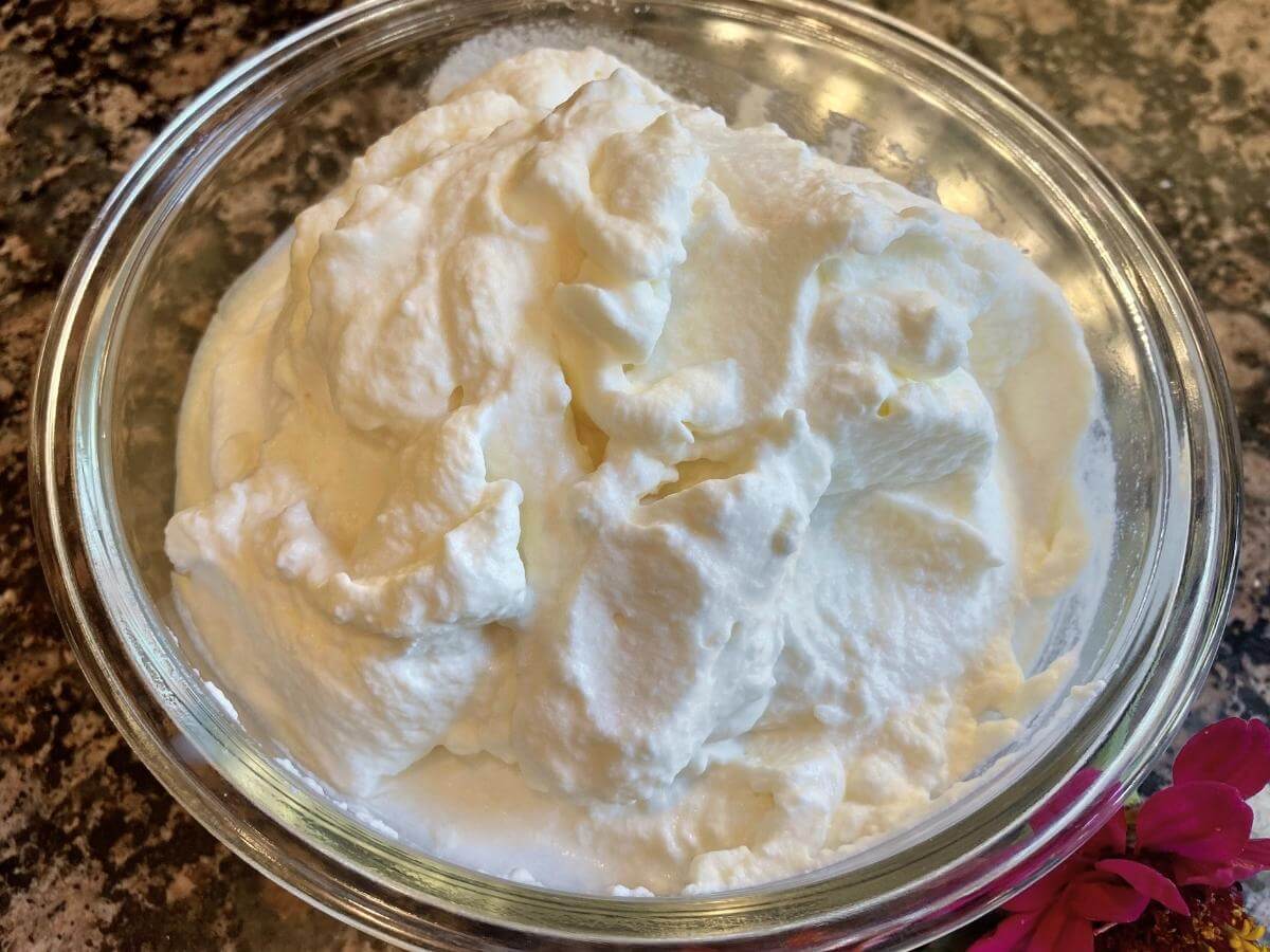 Closeup of whipped cream in a glass bowl.