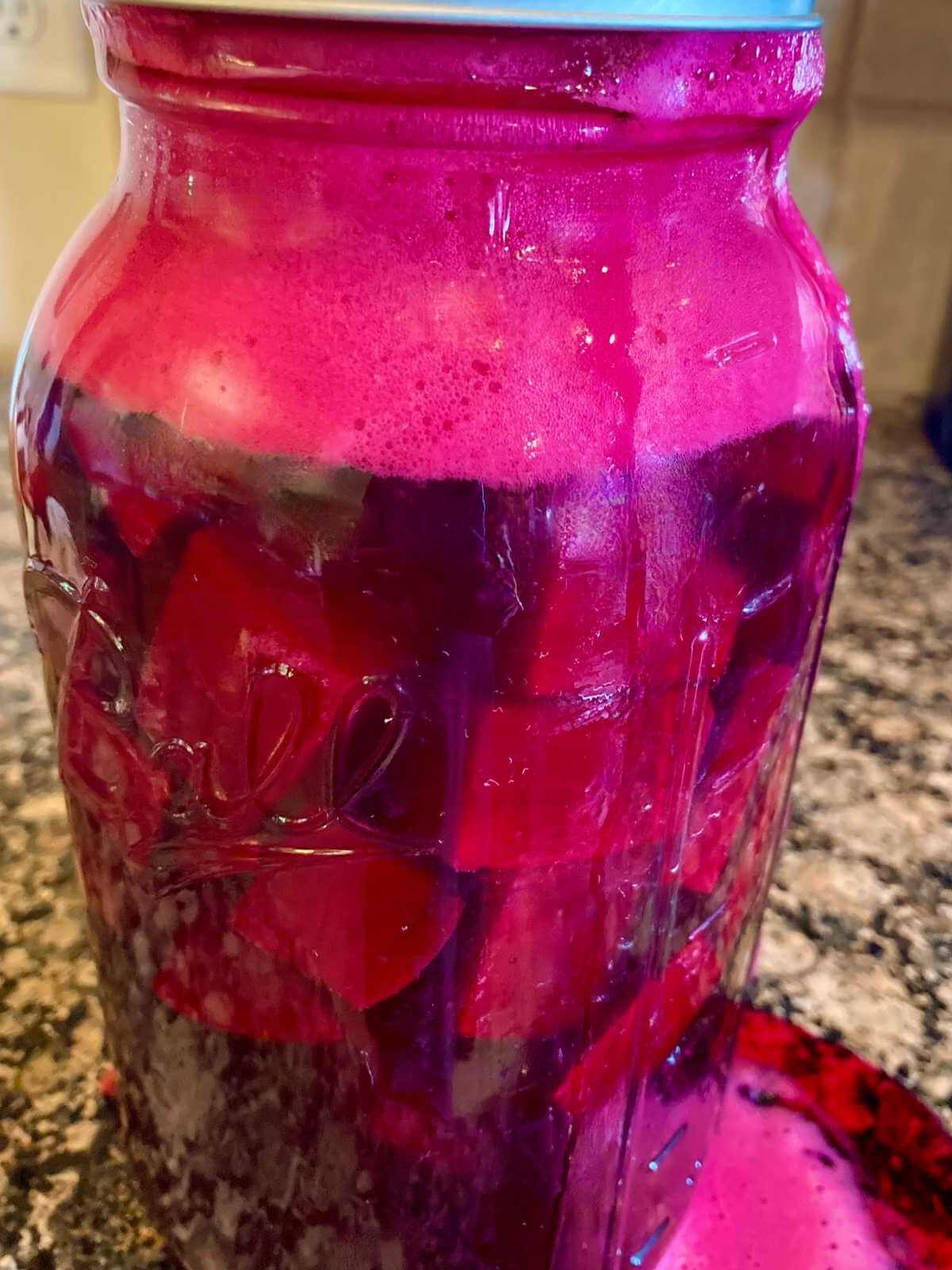 Overflowing mason jar of beet kvass.