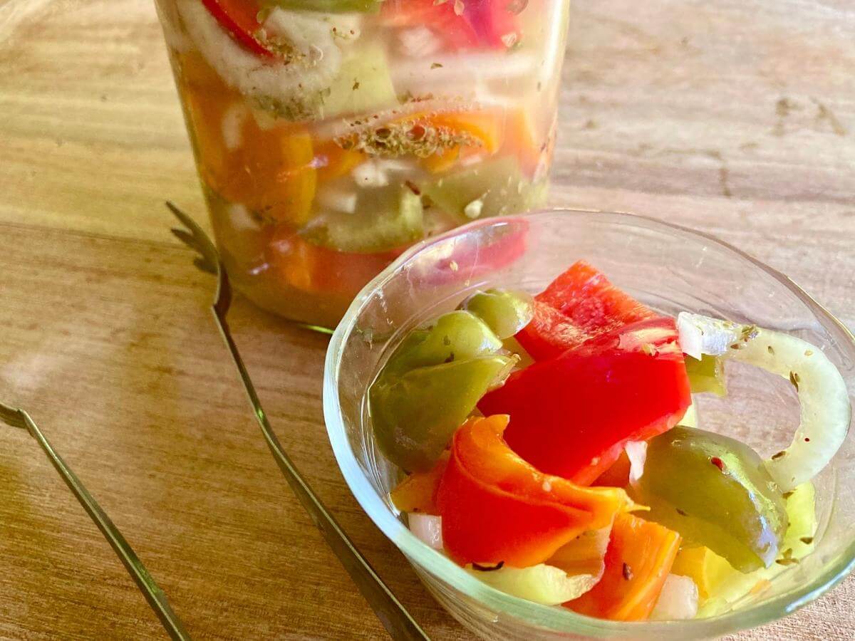 Fermented peppers and onions in a bowl with a utensil for serving.