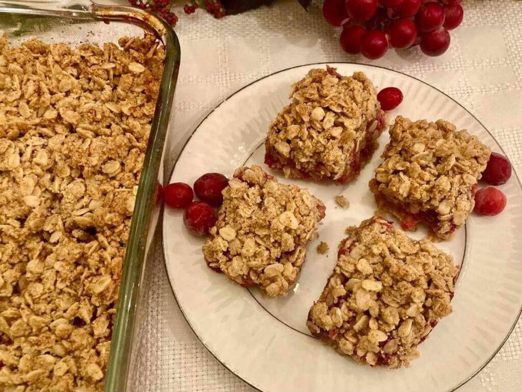 Gluten-free cranberry crisp bars on a plate beside uncut crisp bars.