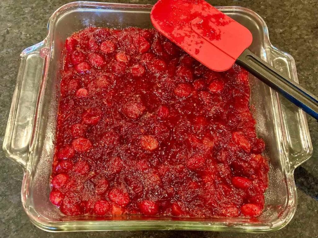 Spreading cranberry sauce on top of crust.