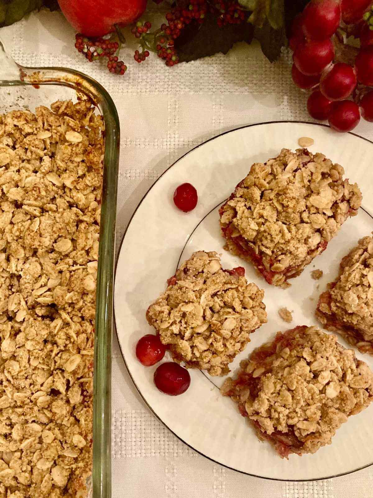 Gluten-free cranberry crisp bars on a plate beside pan with more bars.
