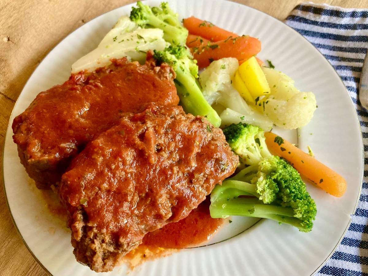 Gluten-free meatloaf on a plate with vegetables.