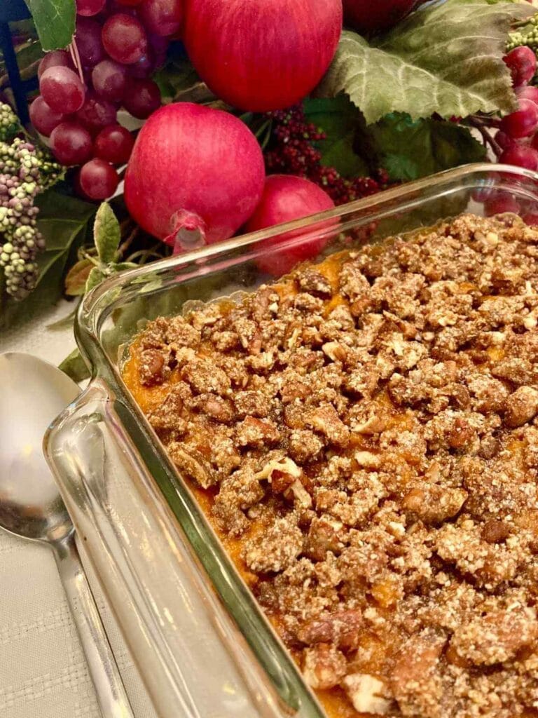 Gluten-free sweet potato casserole in a glass baking dish with a spoon.