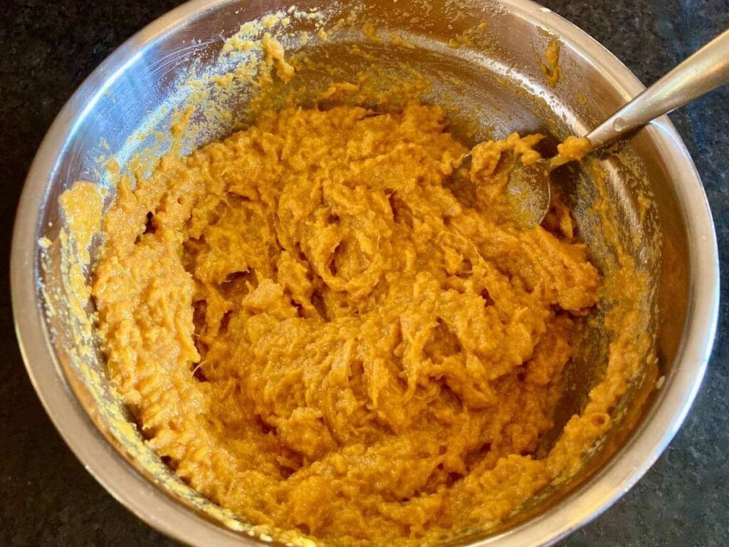 Stirring sweet potato mixture in a mixing bowl.