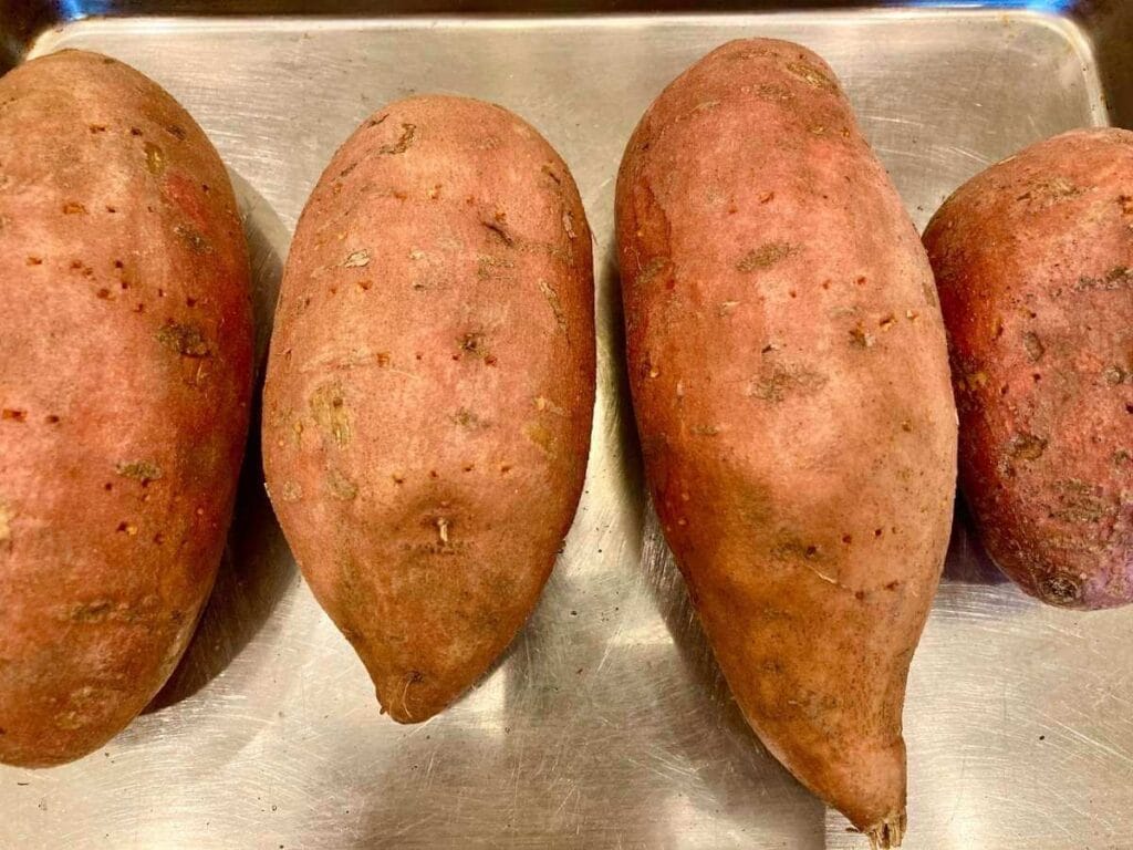 Unbaked sweet potatoes on a baking sheet.