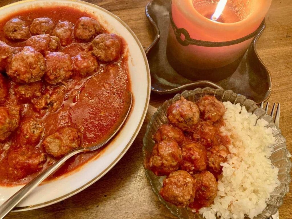 Gluten-free meatballs in a serving dish and a bowl with meatballs and cauliflower rice.
