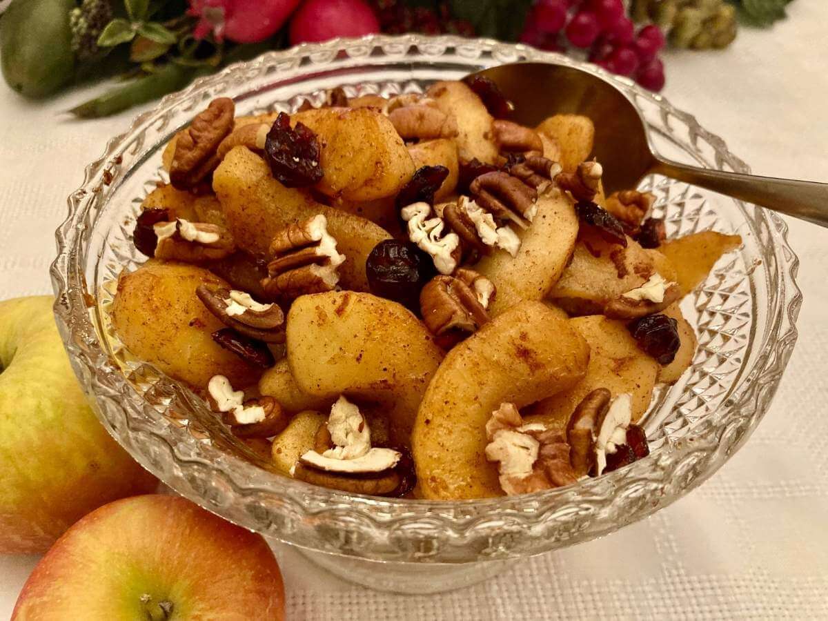 Healthy fried apples in a serving dish with a serving spoon.