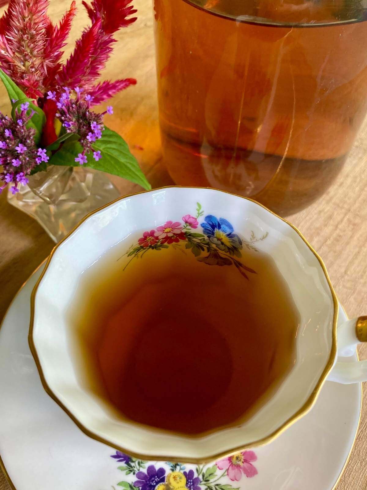 Tea in a teacup with a saucer with fresh flowers.