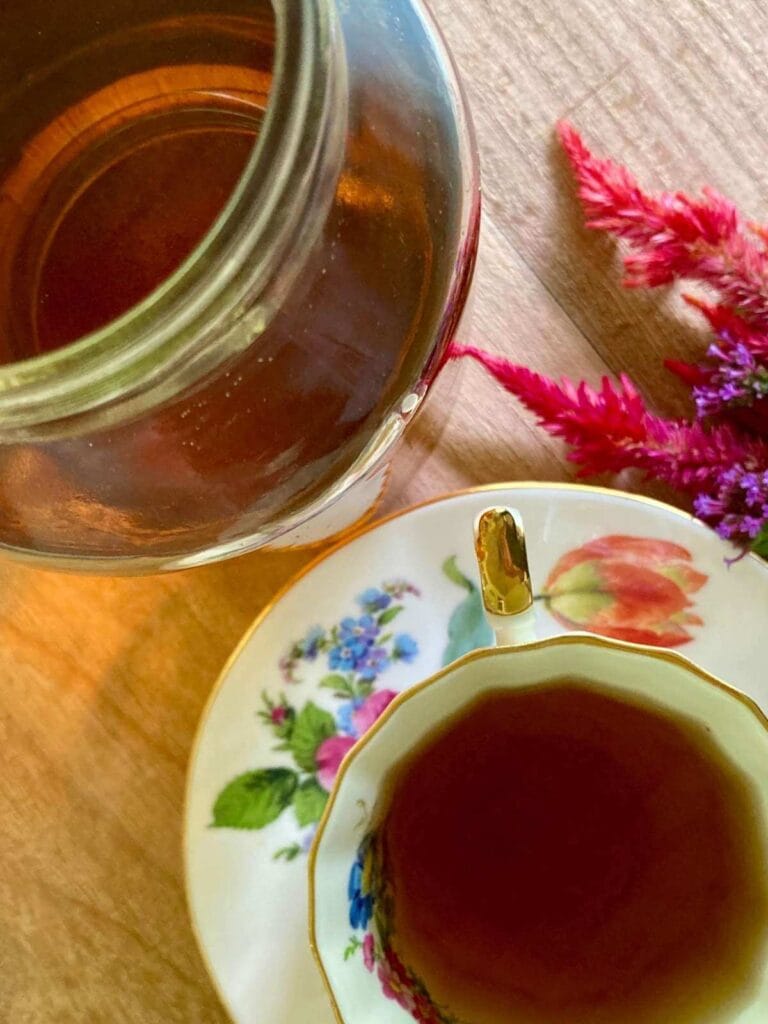 NORA tea in a floral teacup with saucer and a mason jar.