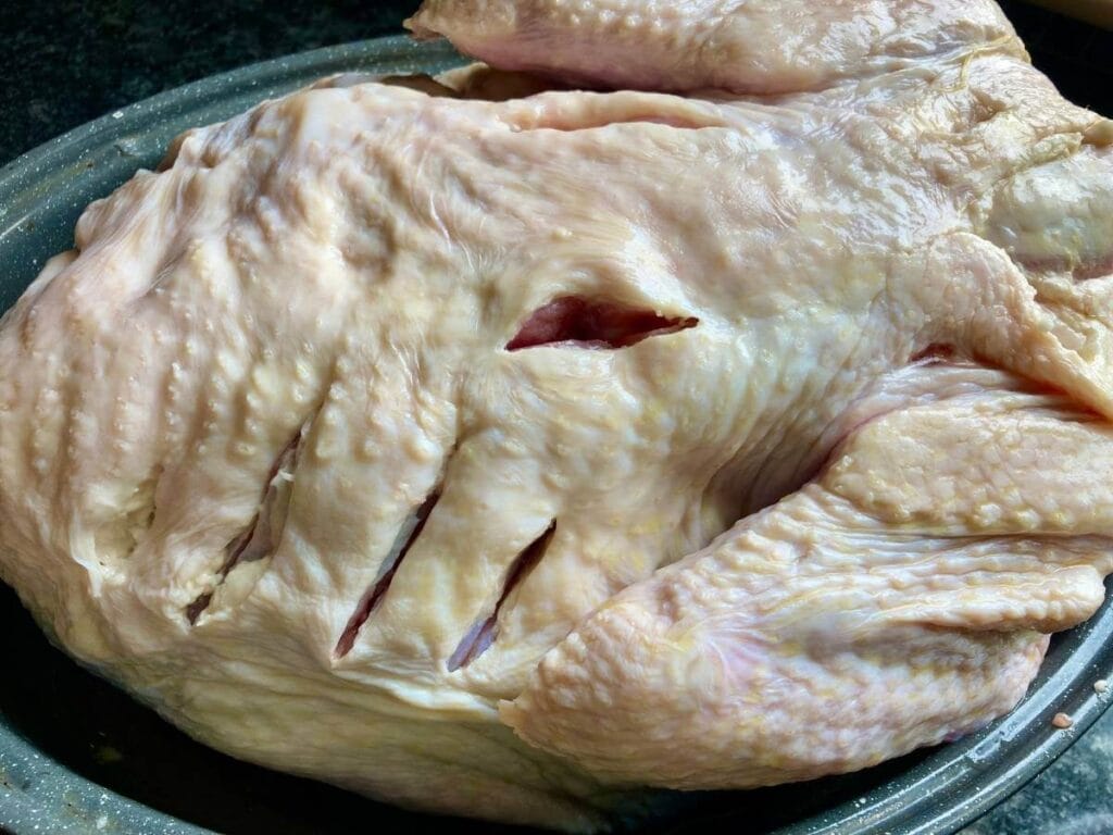 Raw turkey with slits cut in it.