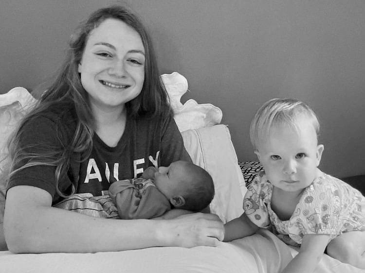 Mother holding a baby and toddler sitting beside her