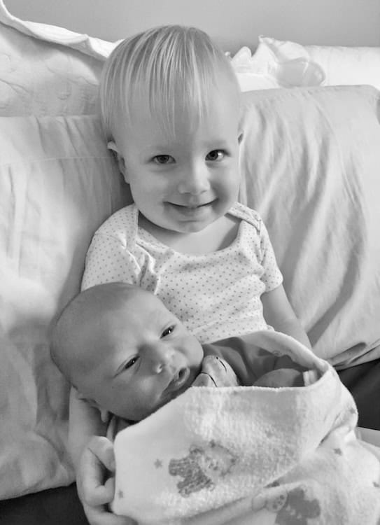 Toddler holding swaddled baby