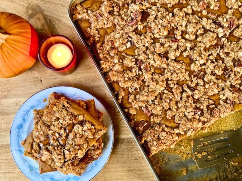 A pumpkin sheet pan pancake topped with streusel on a plate and on a sheet pan.