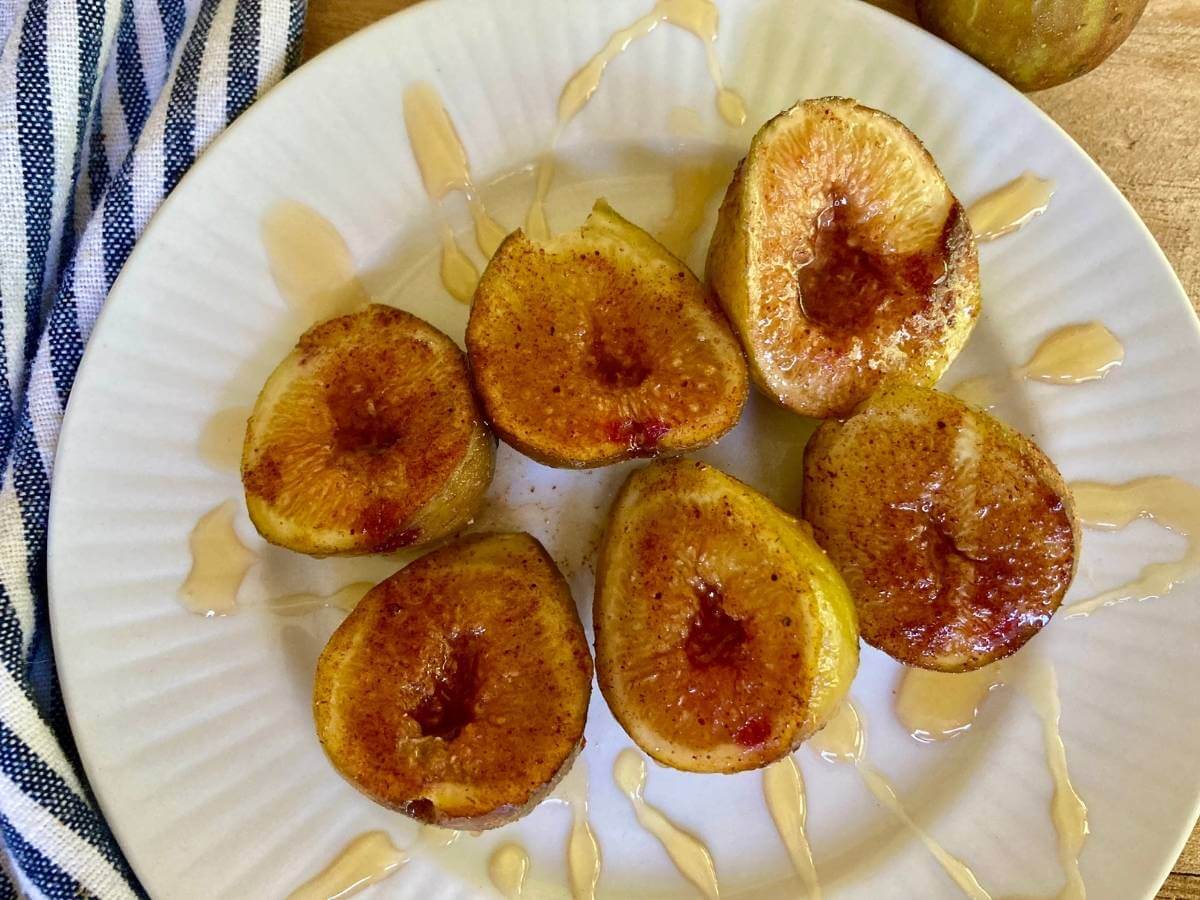 Roasted figs on a plate drizzled with honey.