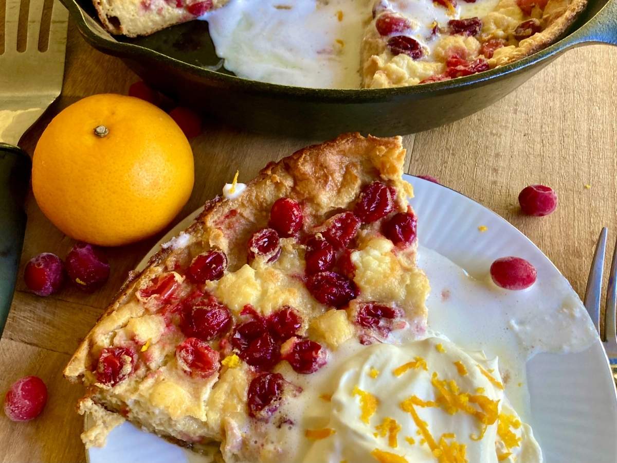 slice of cranberry cheesecake dutch baby with rest of pancake in background