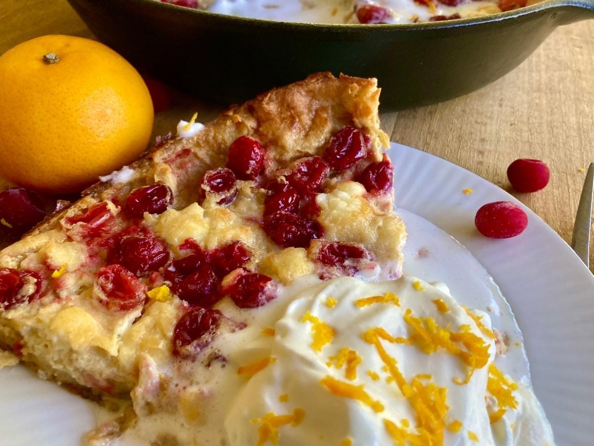 slice of cranberry cheesecake dutch baby with whipped cream