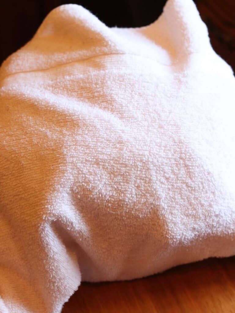 Pot of warm milk and yogurt starter wrapped in a white towel to keep it warm during the fermentation process.