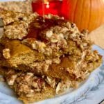 3 stacked slices of Pumpkin Crisp Sheet-Pan Pancakes with syrup