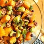 Closeup of roasted Brussels sprouts and butternut squash with pecans and cranberries in a bowl.
