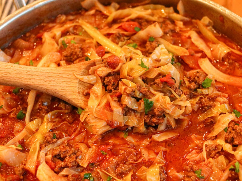 Cabbage bowls in a saute pan and on a wooden spoon.