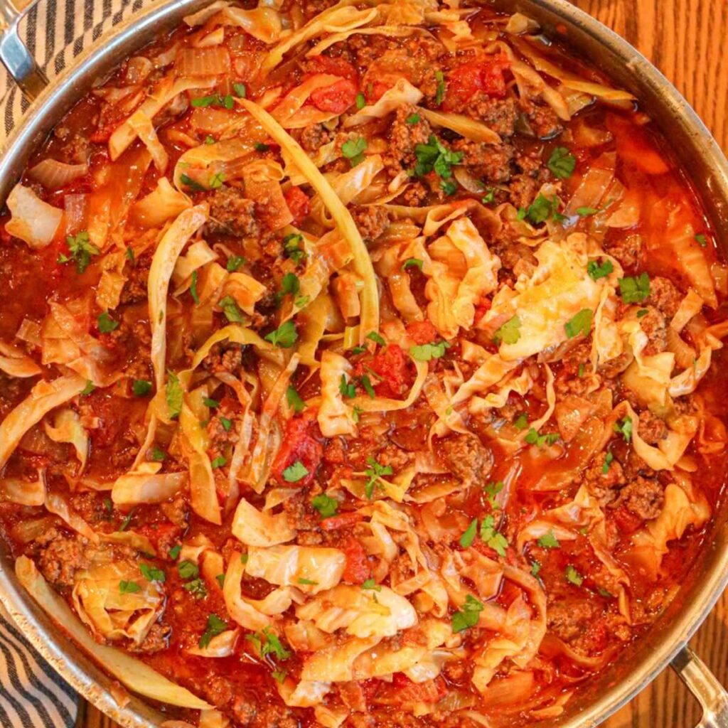 Closeup view of cabbage bowls in a sauté pan topped with chopped parsley.