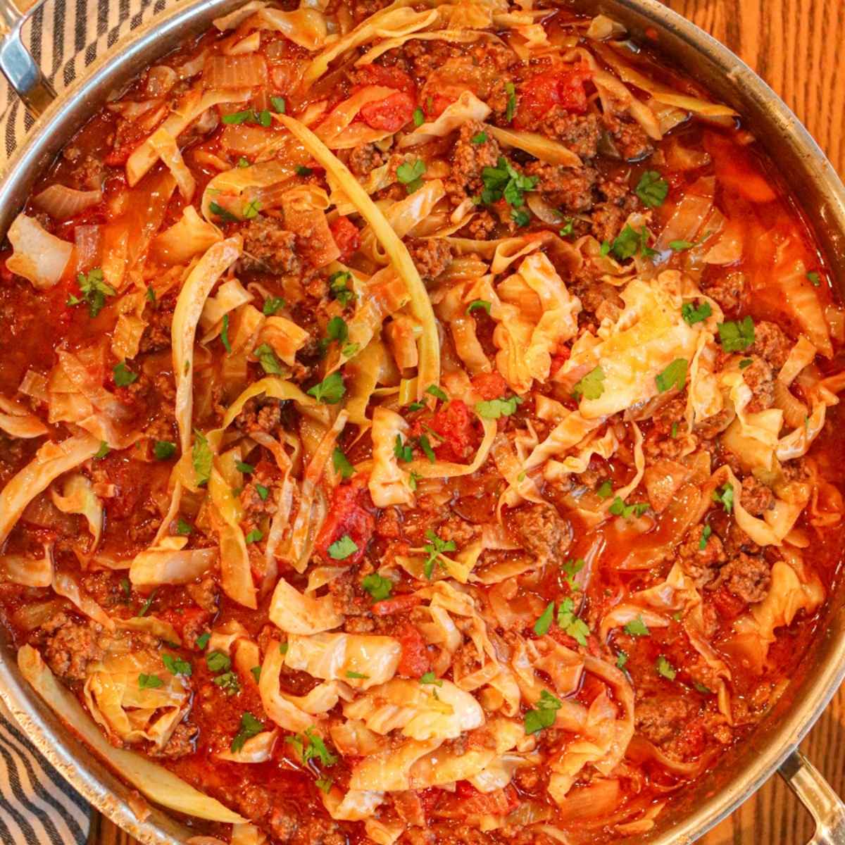 Closeup view of cabbage bowls in a sauté pan topped with chopped parsley.
