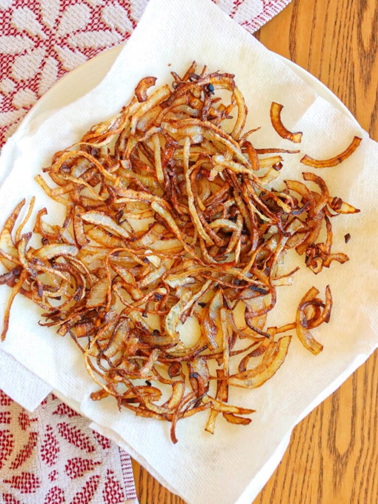 Flour-free fried onions cooling on a paper towel.