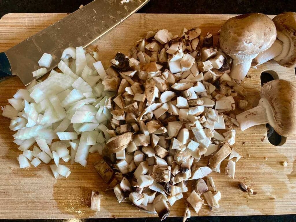 Chopping mushrooms and onions on cutting board