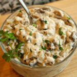 Closeup of a spoon in a bowl of condensed gluten-free cream of mushroom soup.