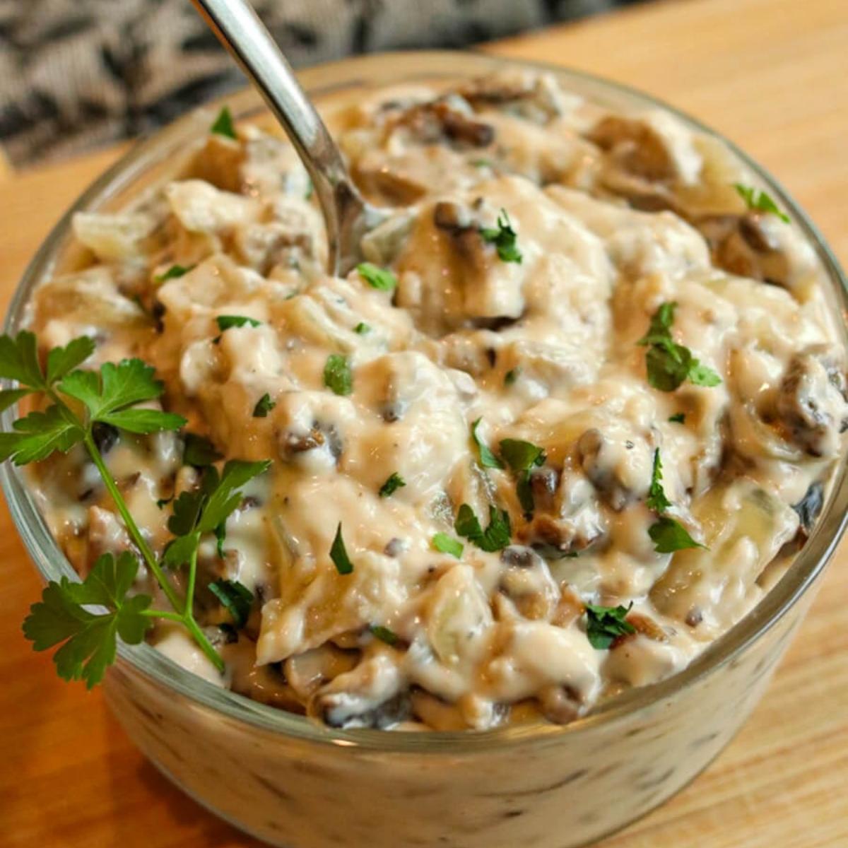 Closeup of a spoon in a bowl of condensed gluten-free cream of mushroom soup.