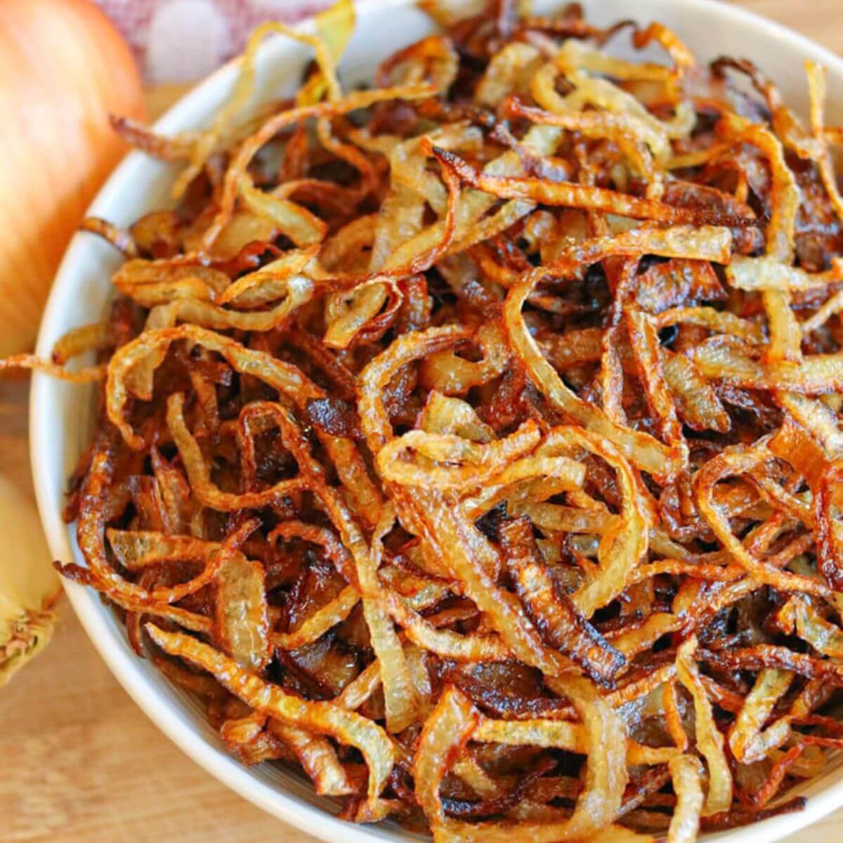 Closeup view of fried onion slices in a white bowl.