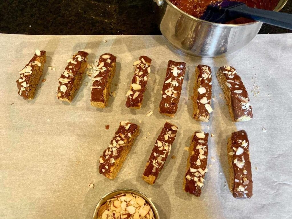 Dipping biscotti in chocolate and almonds