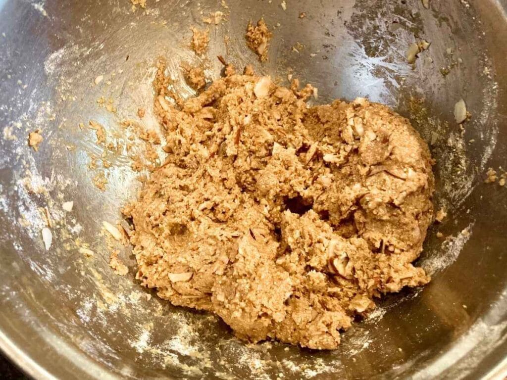 Dough with almonds in mixing bowl