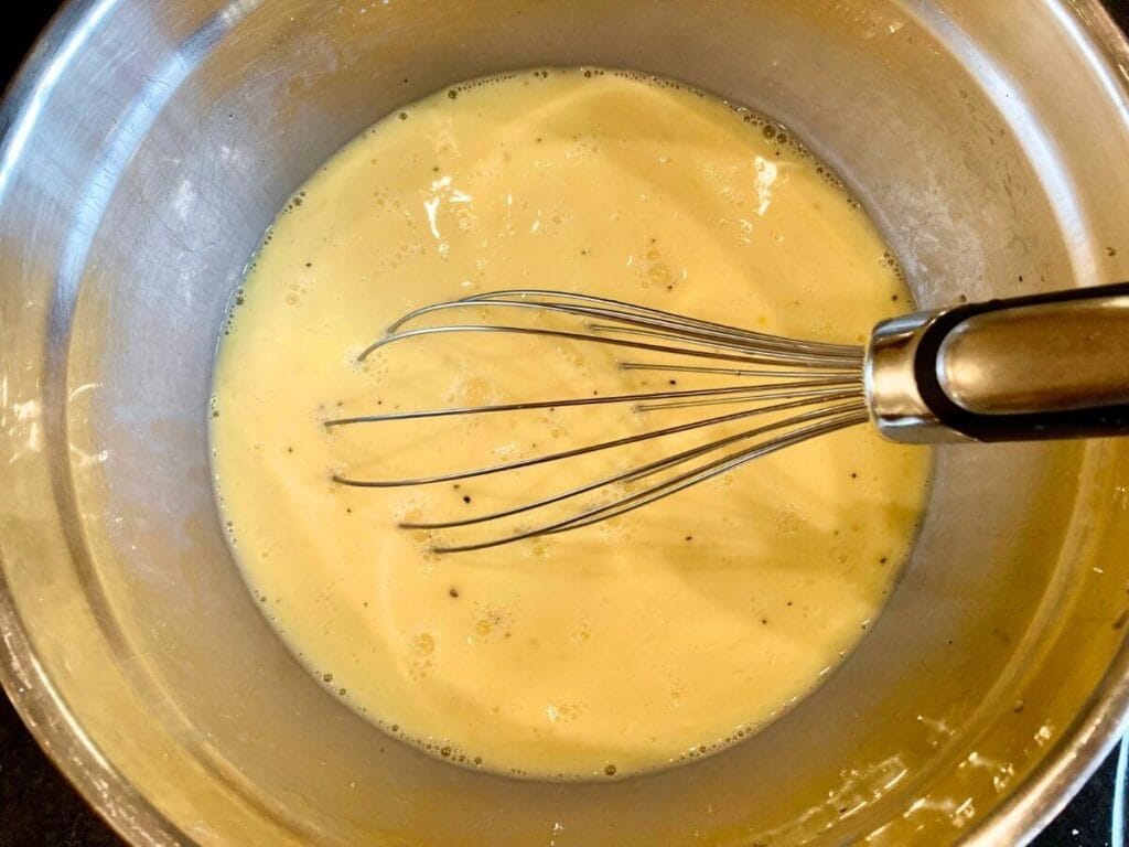 Whisking eggs and milk together in a mixing bowl