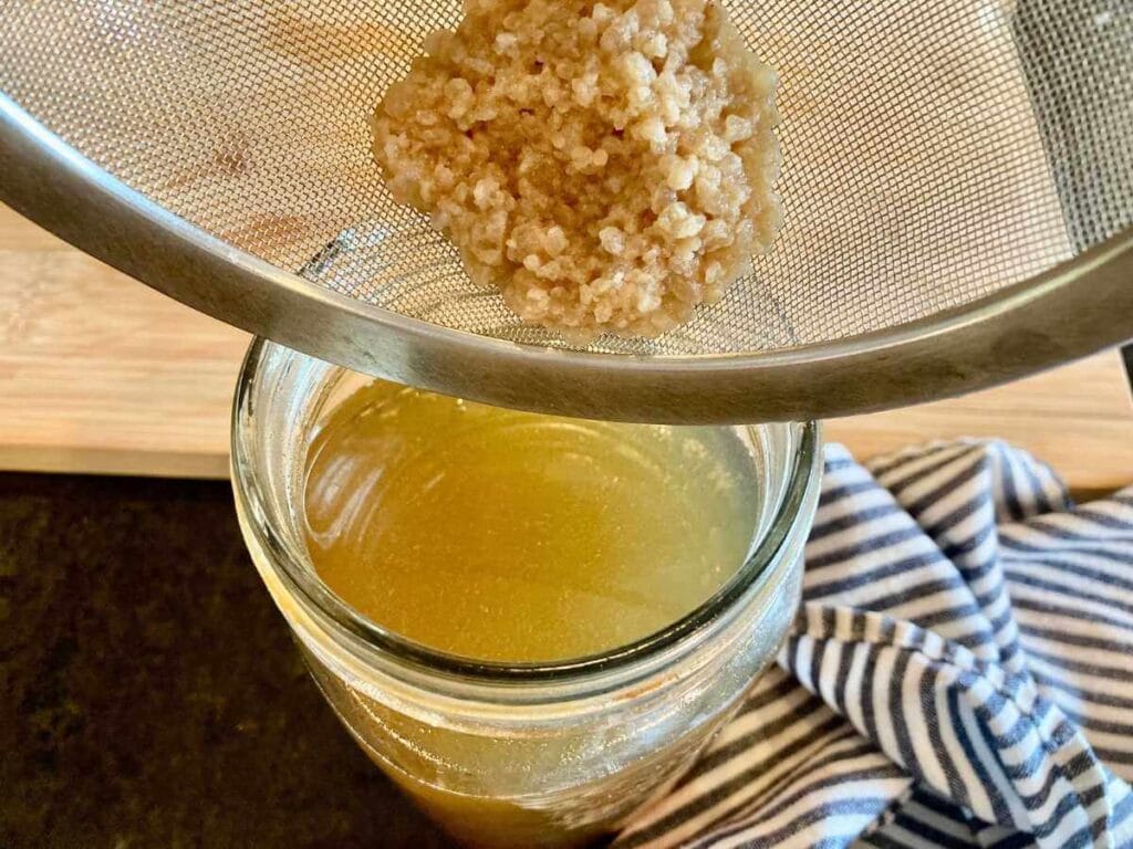 Pouring water kefir grains into jar with sugar water