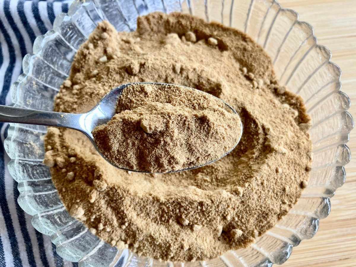 Spoon scooping powdered coconut sugar out of bowl
