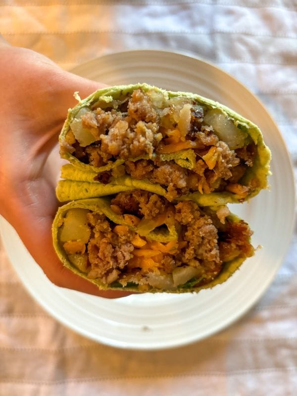 hand holding two breakfast burritos