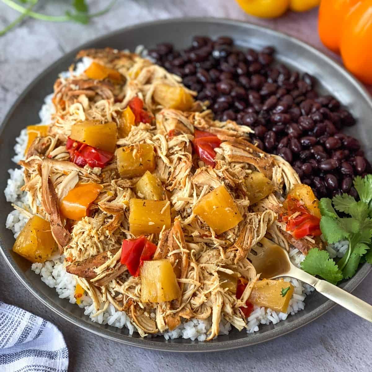 jerk chicken over rice with cilantro and black beans on a plate