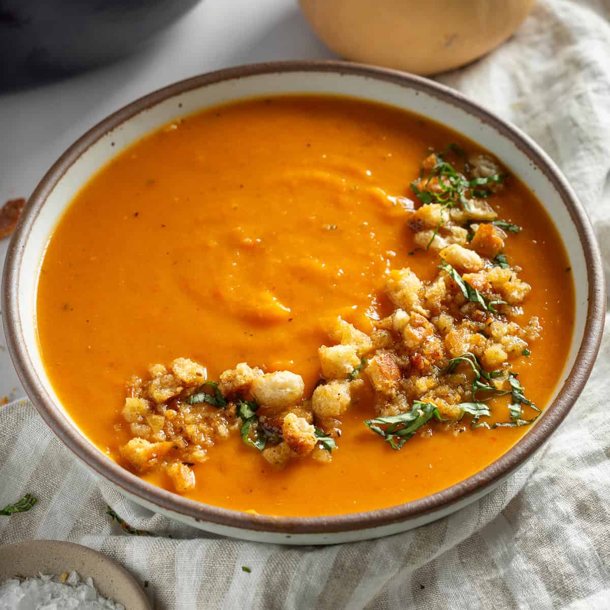 butternut squash and red pepper soup topped with croutons in a bowl