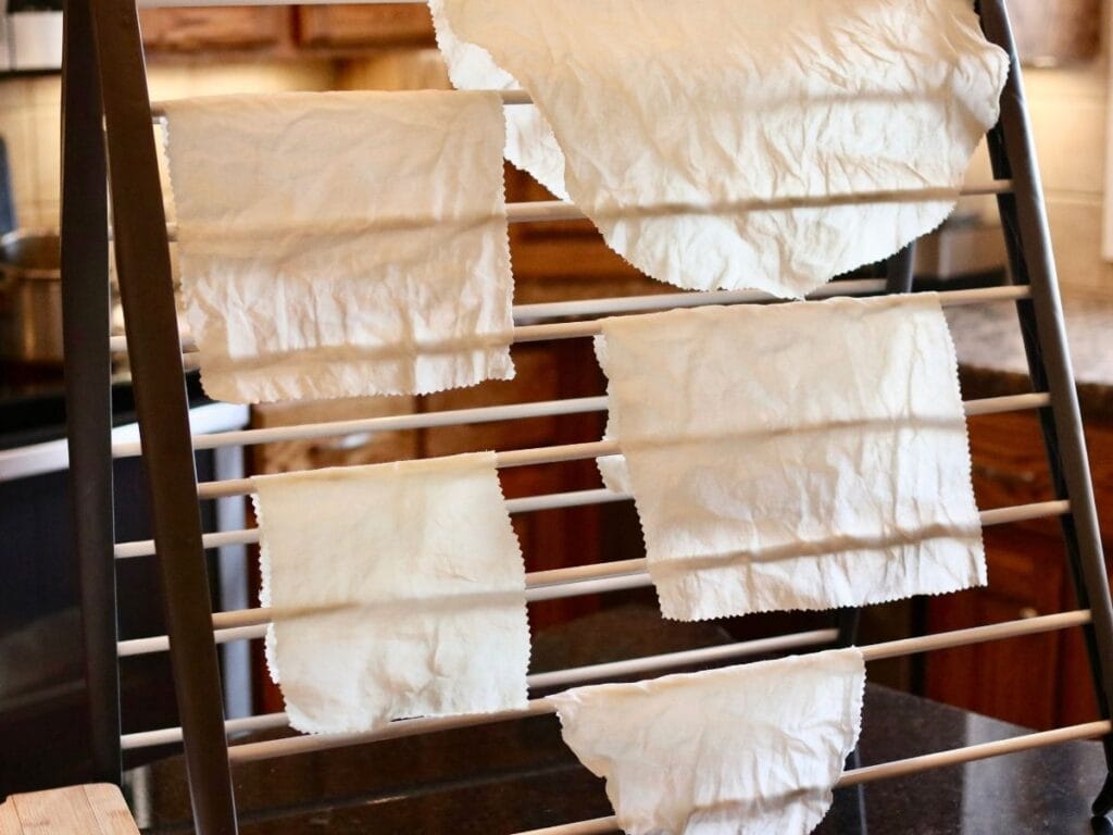 Beeswax food wraps hanging to dry on drying rack in kitchen.