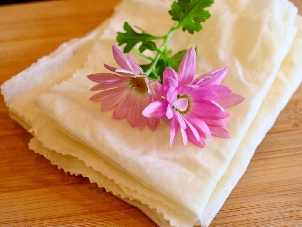 Stack of beeswax food wraps with two flowers on top.