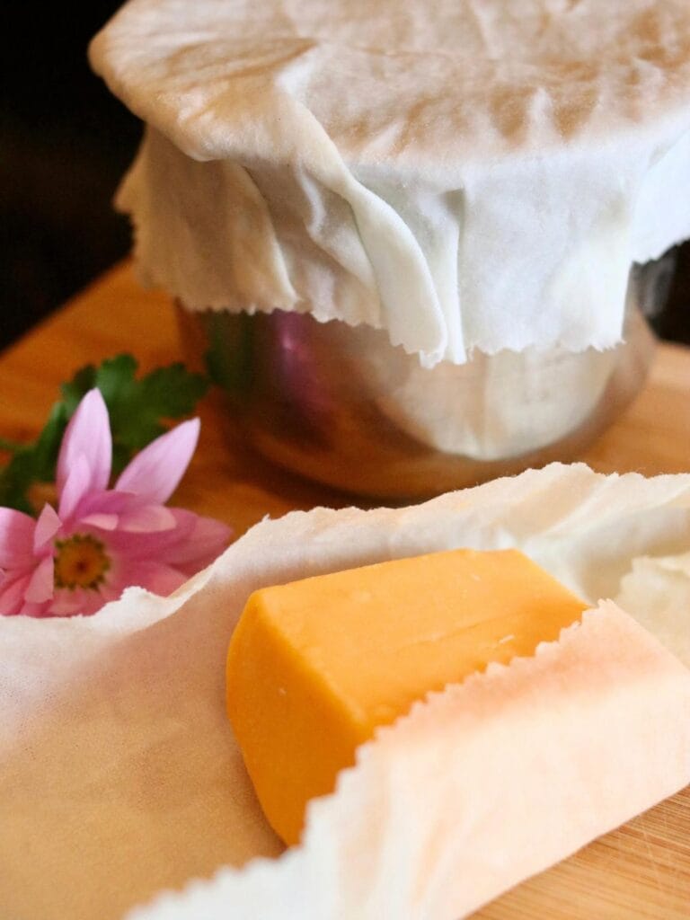 Cheese partially wrapped in beeswax food wrap with a bowl covered with beeswax food wrap