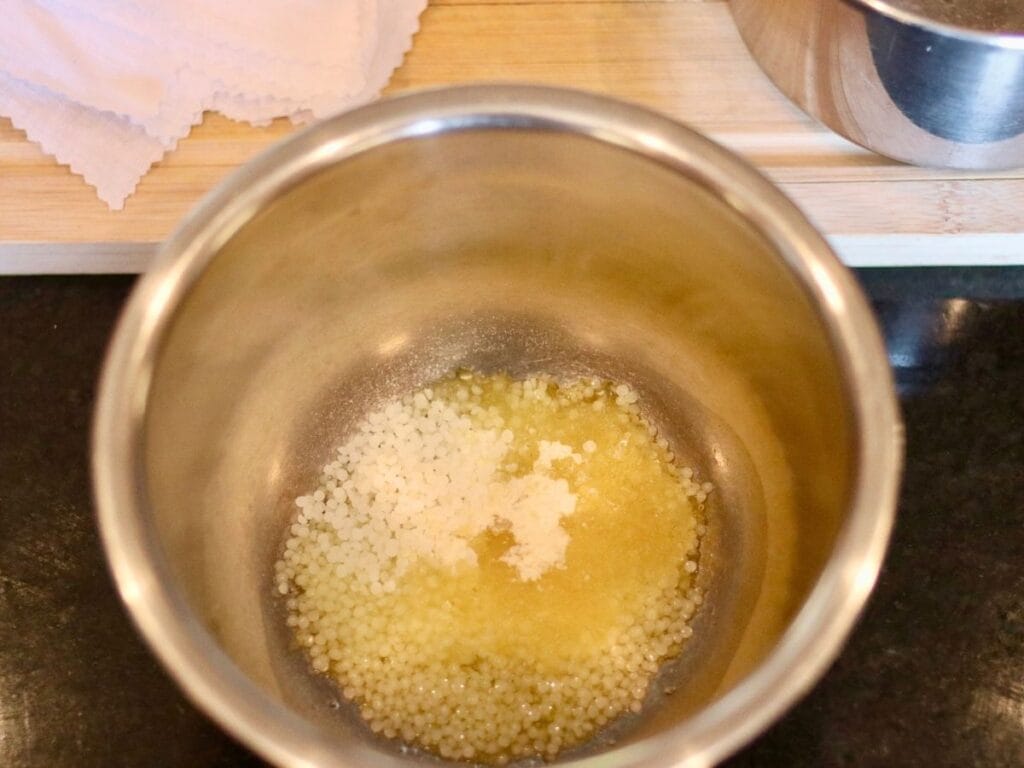 Beeswax pastilles, jojoba oil, and pine resin in a bowl.