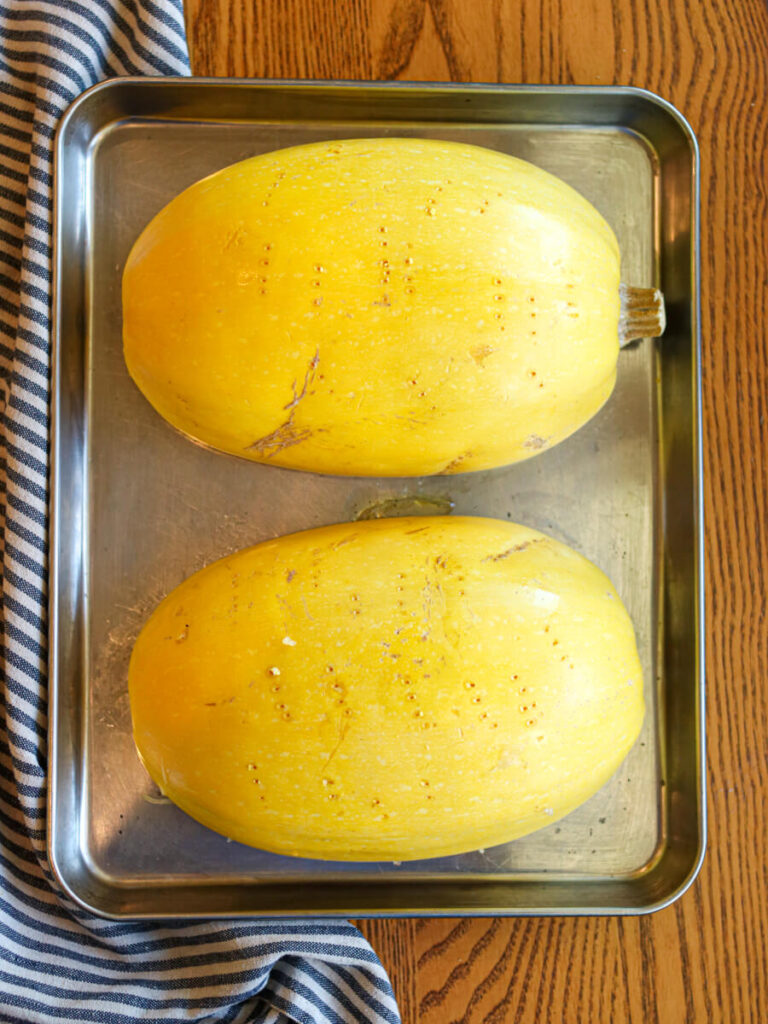 Spaghetti squash halves ready to roast on a pan.