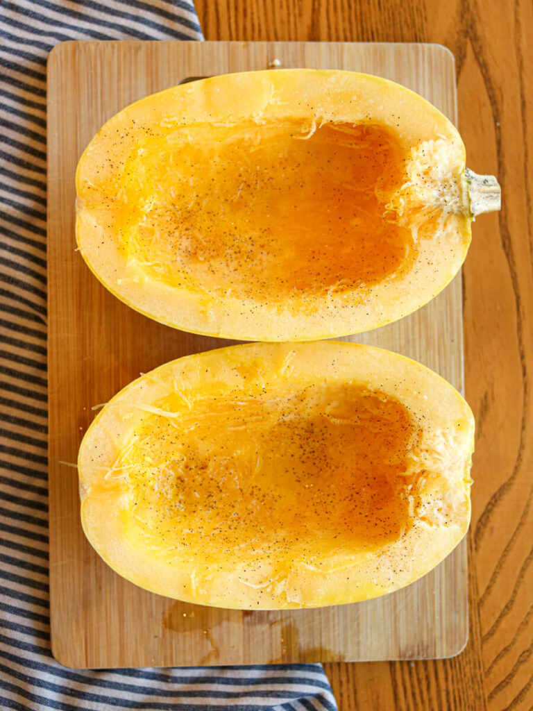 A spaghetti squash cut in half on a wood cutting board.
