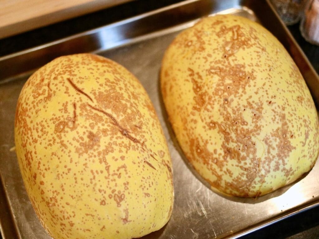 Spaghetti squash halves face down on a baking sheet