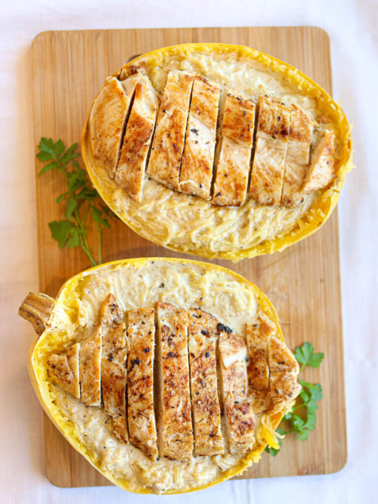 Two spaghetti squash shells filled with chicken Alfredo spaghetti squash and topped with sliced chicken.