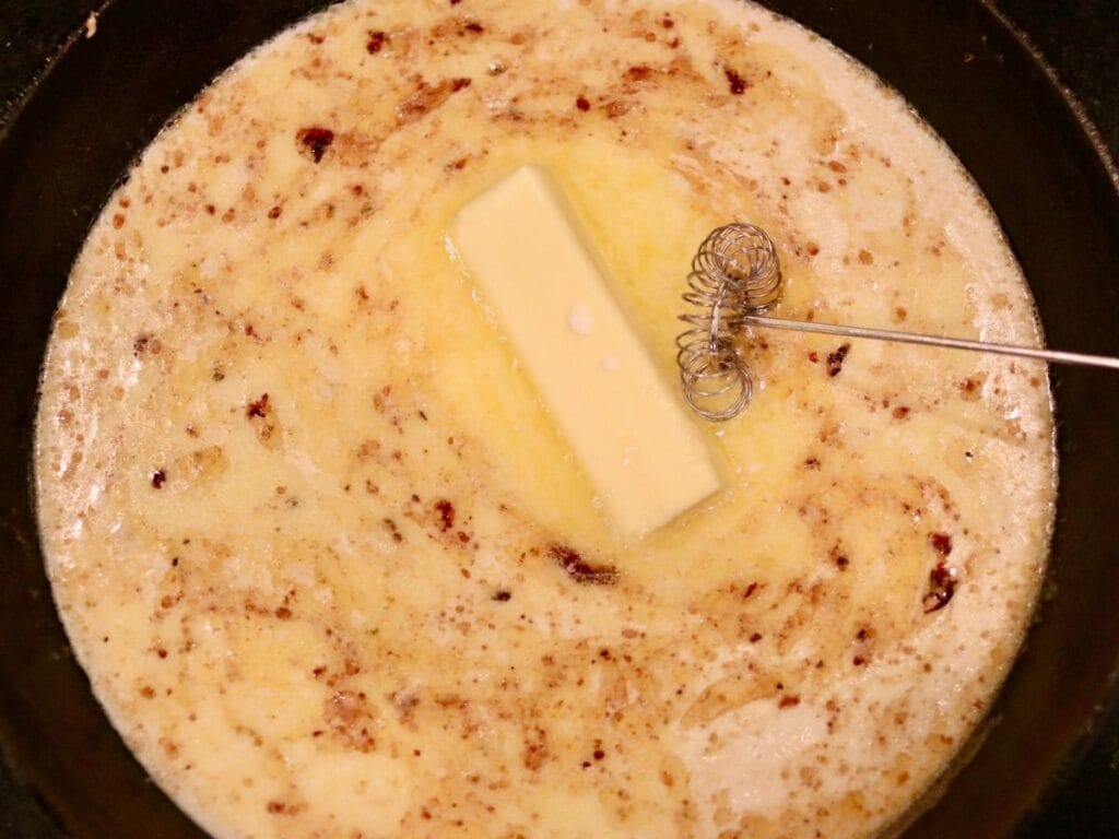 Whisking butter and cream in a cast iron skillet